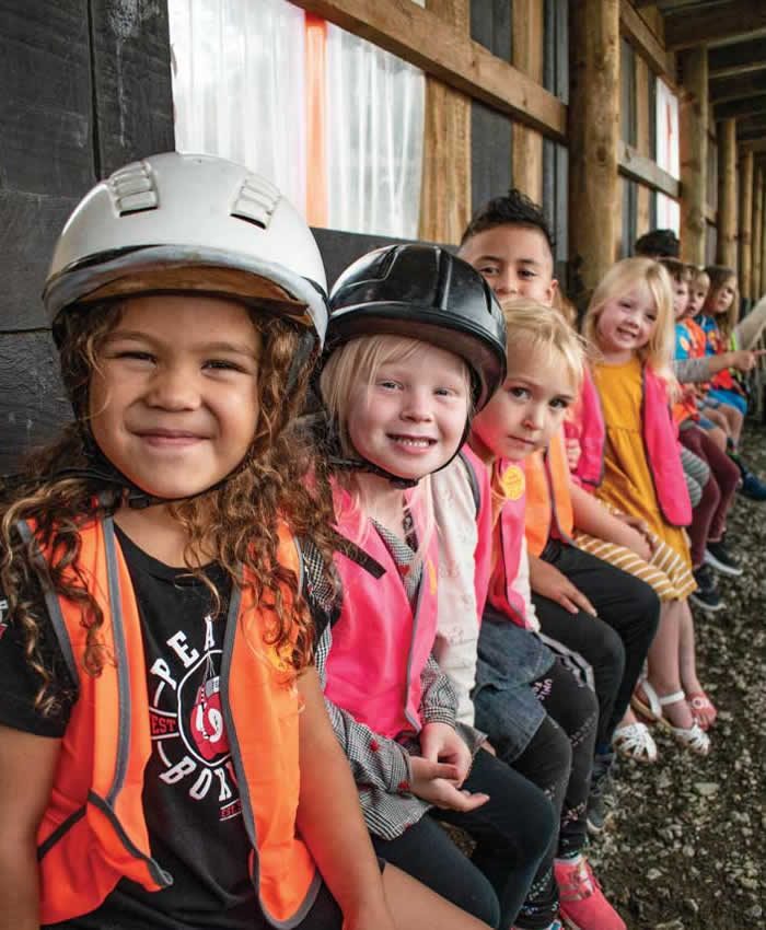 Children in riding helmets grinning