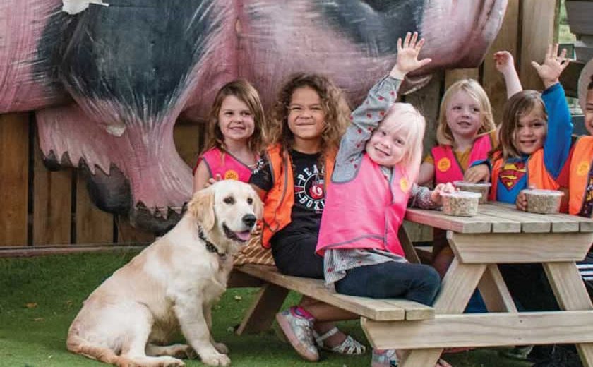 A preschool group waving beside the big pig